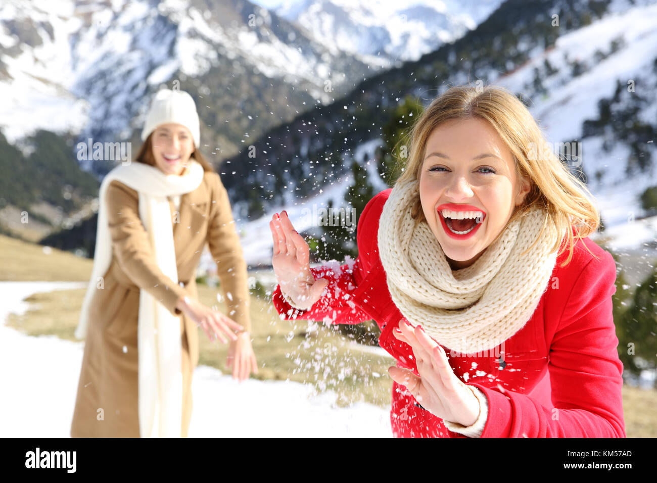 Due amici scherzando tirare palle di neve su vacanze in una montagna innevata in inverno Foto Stock