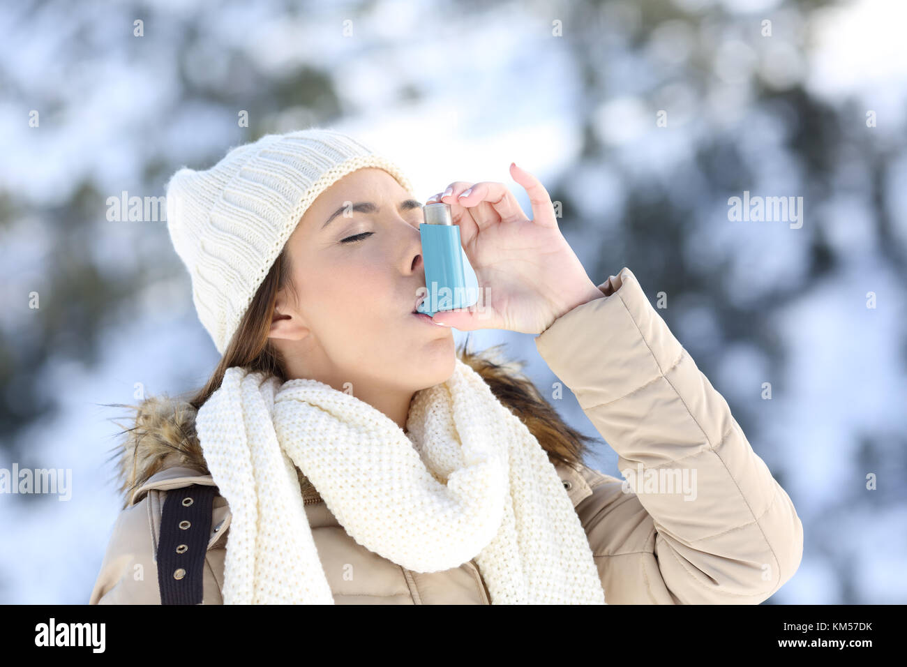 Ritratto di una donna con un inalatore per asmatici in un freddo inverno con una montagna innevata in background Foto Stock