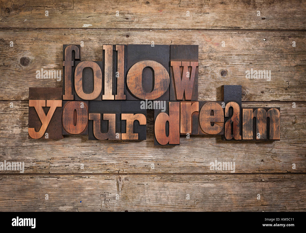 Segui il tuo sogno, una frase insieme con l'annata tipografia su blocchi di legno rustico sfondo Foto Stock