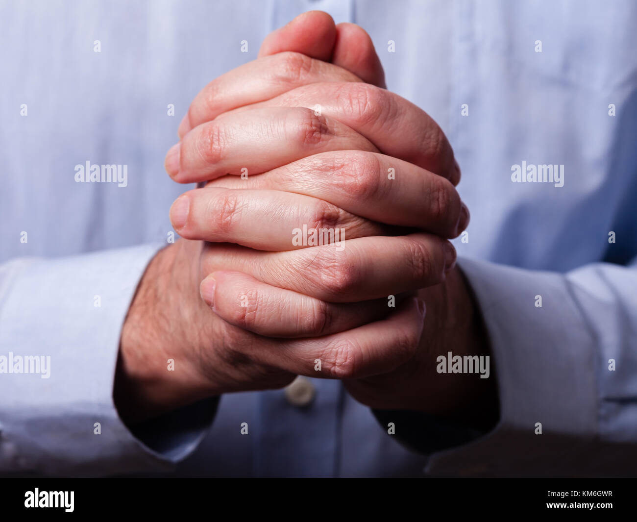 Chiudere in su o in primo piano delle mani di fedeli uomo maturo pregando. mani giunte, interlacciato, dita in adorazione a Dio. concetto per la religione e la fede, la preghiera di un Foto Stock