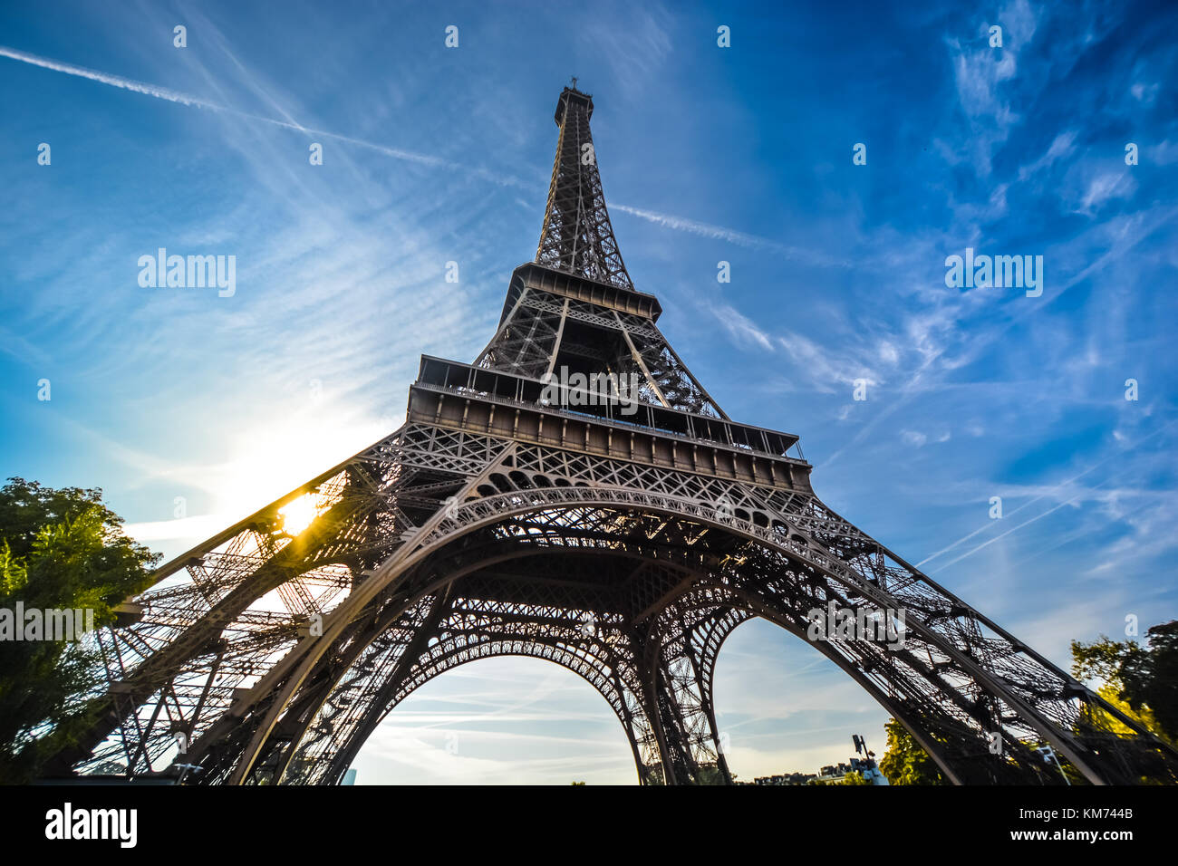 Una vista della Torre Eiffel con un obiettivo grandangolare guardando verso l'alto dalla base in un pomeriggio soleggiato Foto Stock