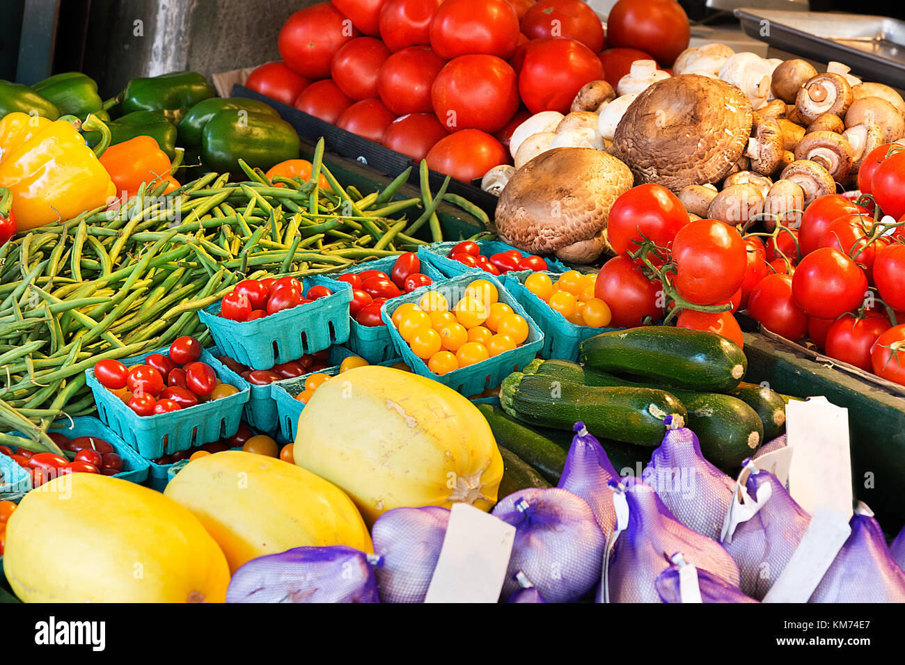 Melanzane, pomodori ciliegia di pomodoro, aglio, funghi e altri ortaggi su cavalletti in un mercato pubblico a Seattle, Washington. Foto Stock