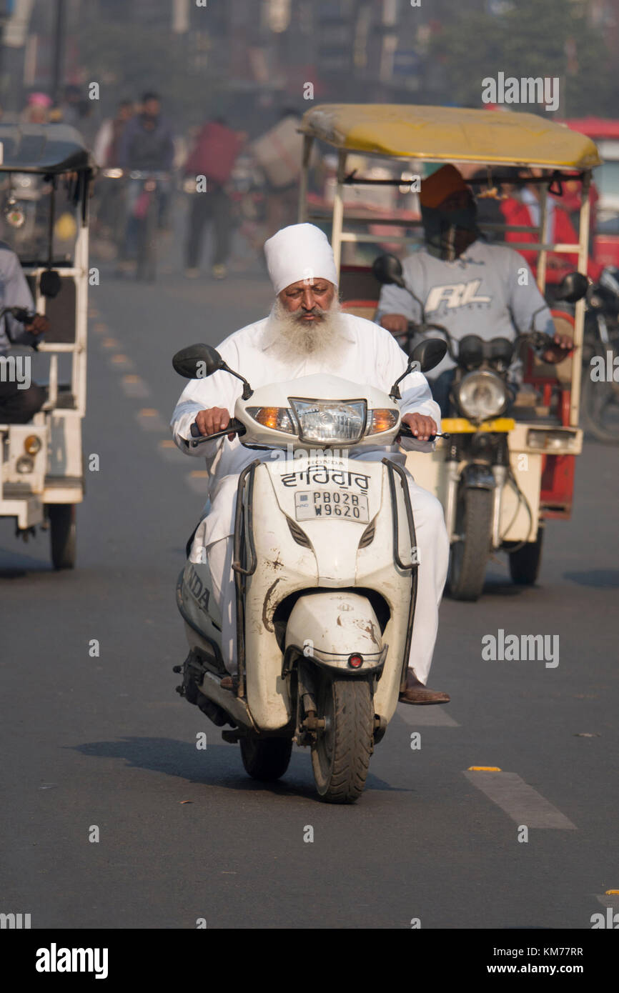 Punjabi uomo musulmano con una lunga barba bianca rides scooter di Amritsar, India Foto Stock