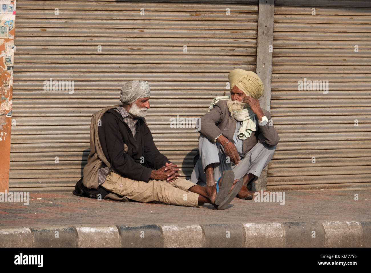 Due sikh punjabi gli uomini con la barba bianca e turbanti sedersi a parlare in strada, ad Amritsar punjab Foto Stock