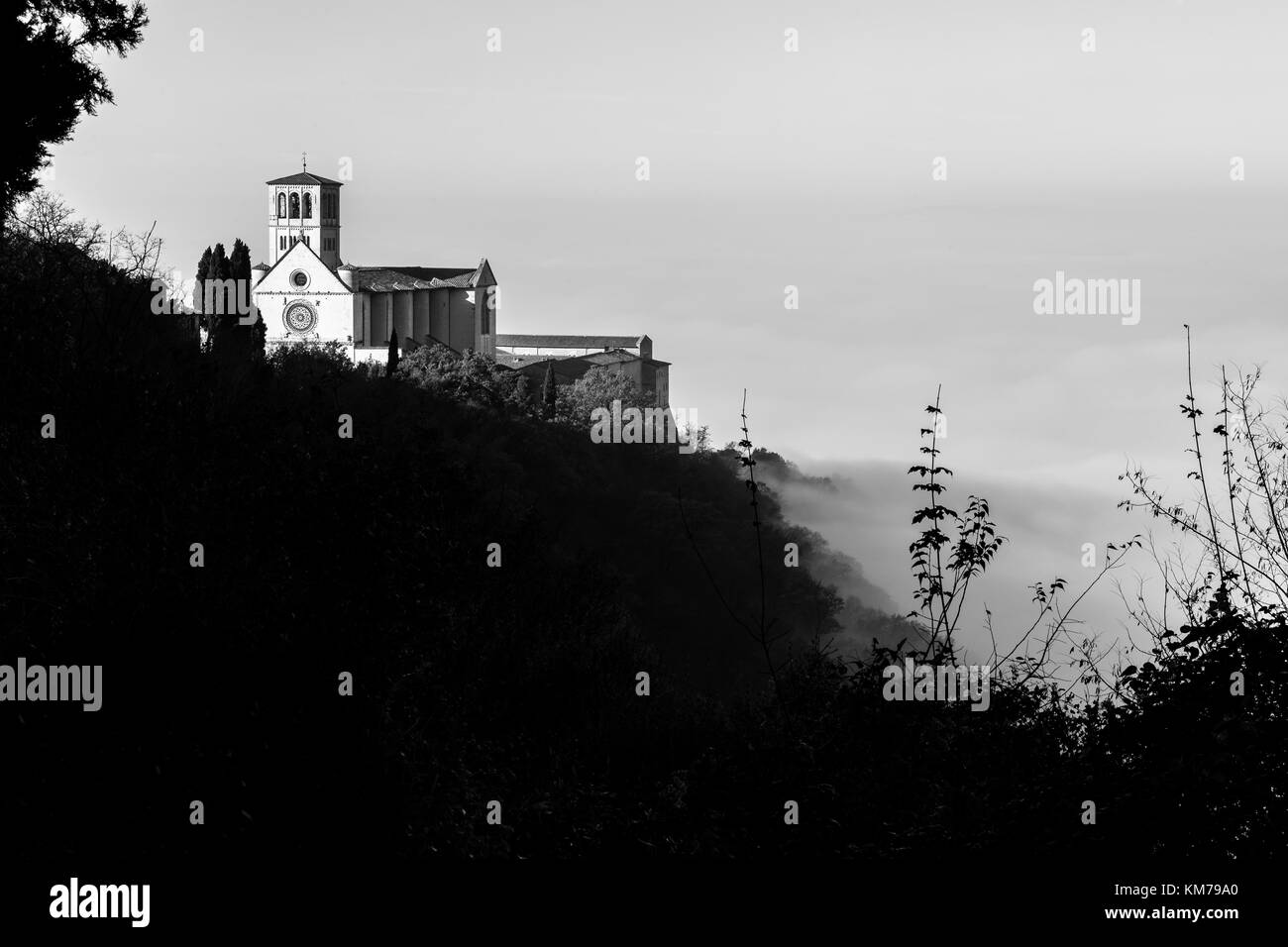 Bellissima vista della Basilica di San Francesco in Assisi (Umbria, Italia), sopra un mare di nebbia Foto Stock
