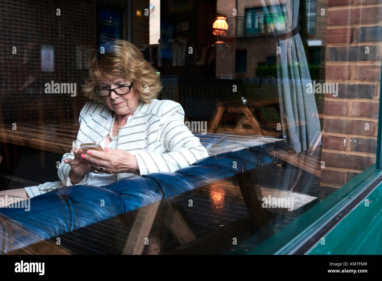 Londra, UK, elegante senior business donna controllando il suo telefono in un coffee shop, senior business donne Foto Stock