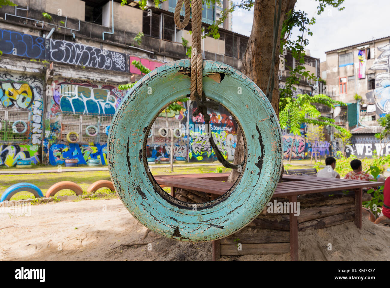 Un vecchio stile tire swing in una città parco giochi per bambini con la vecchia vernice cracking appeso ad un albero da una spessa fune. Foto Stock