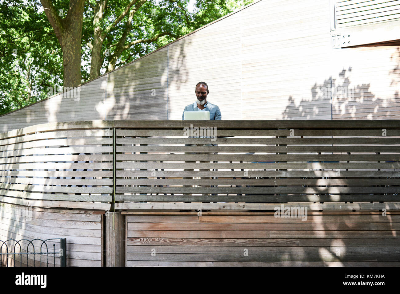 Londra, UK, oltre 50s nero maschio africano lavorando sul suo laptop all'aperto, singolo. Foto Stock