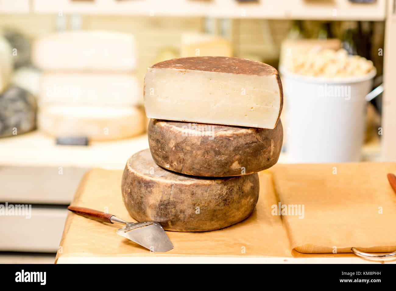 Teste di formaggio stagionato con slicer sul tavolo al negozio di formaggio Foto Stock