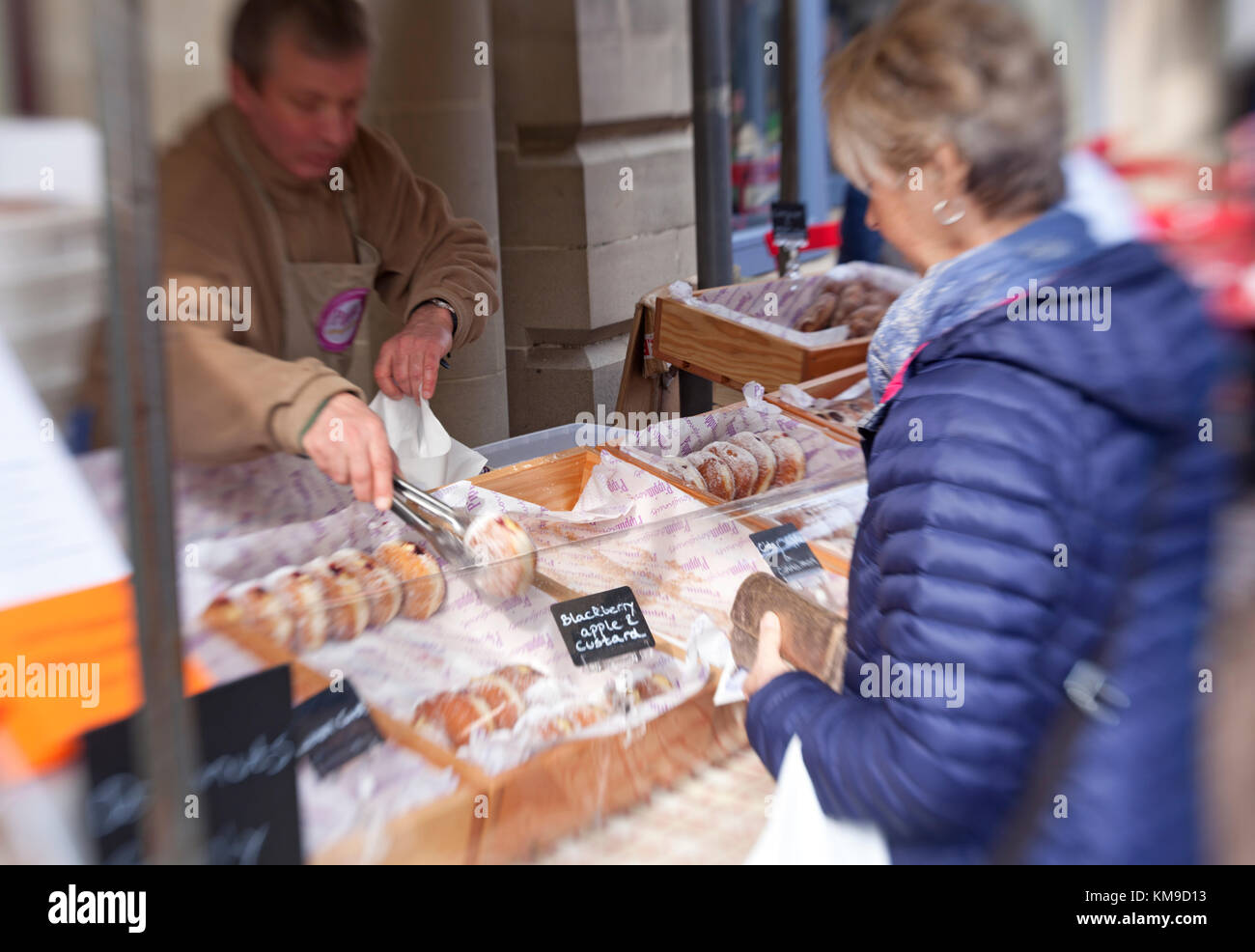 Una donna acquista ciambelle artigianale da uno stallo presso il premiato stroud mercato degli agricoltori nel Gloucestershire, UK Foto Stock