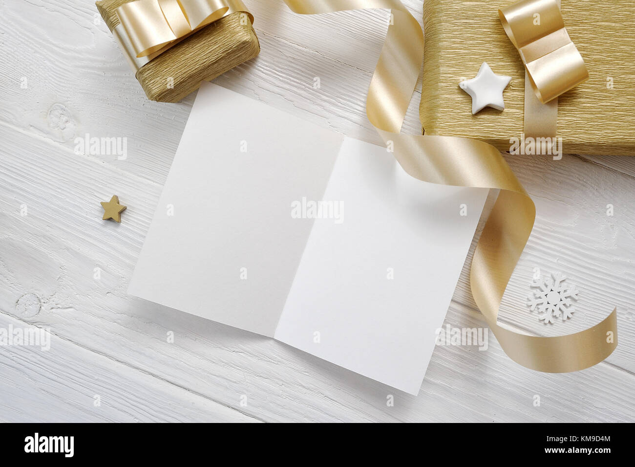 Mockup natale biglietto di auguri con oro nastro regalo, flatlay su un bianco sullo sfondo di legno, con posto per il testo Foto Stock