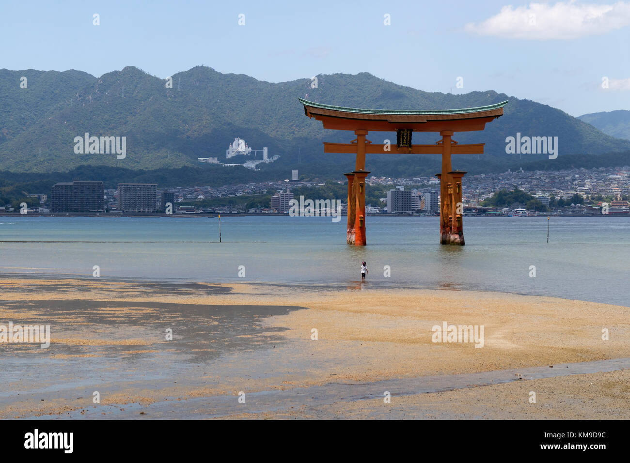 Miyajima - Giappone, 26 maggio 2017: rosso torii gate del santuario di Itsukushima in mare con la bassa marea naer miyajima e con un bambino di fronte alla ricerca fino a che Foto Stock
