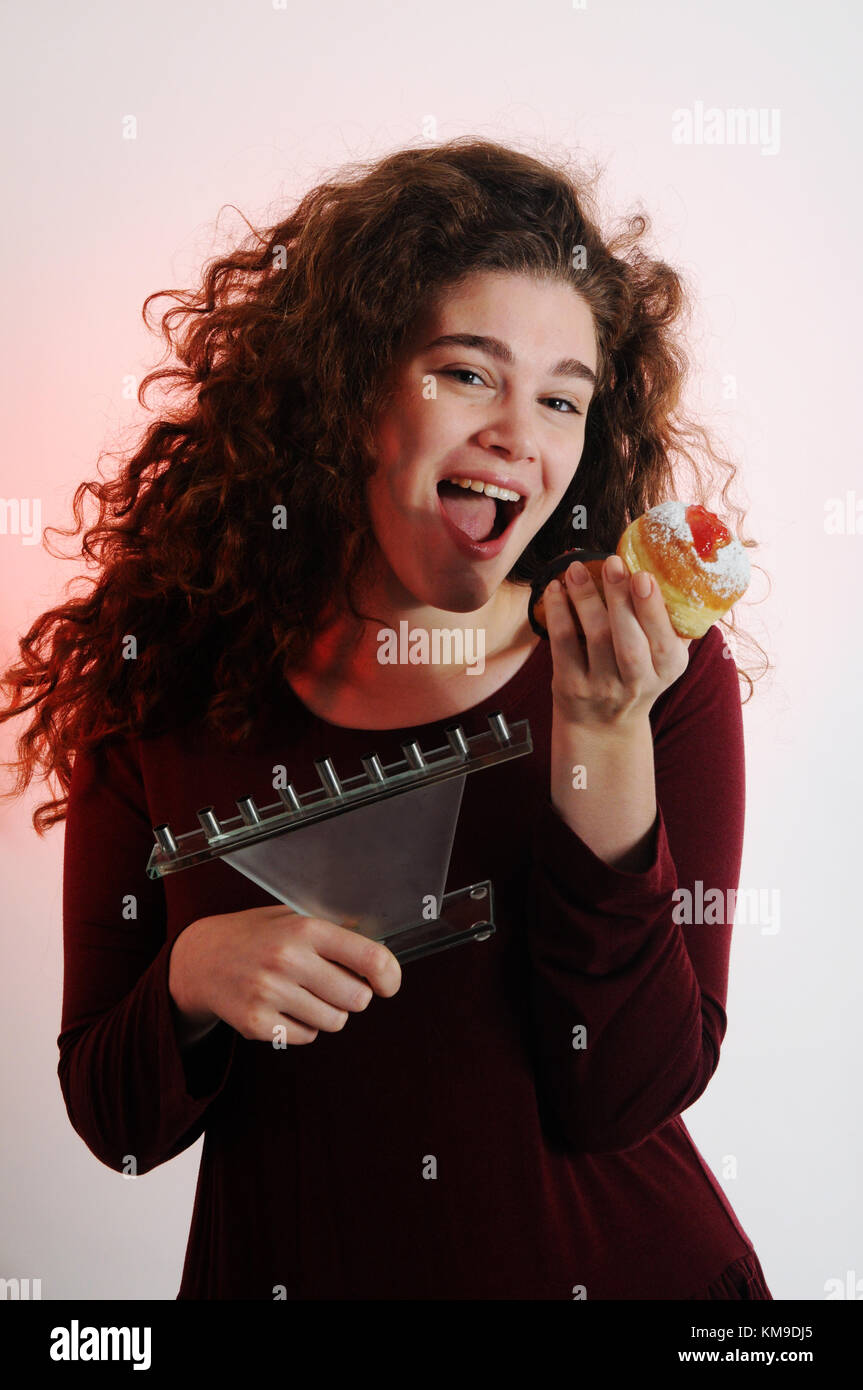 Festa ebraica Hanukkah - bella donna con dolci sufganiyot (ciambelle) e menorah Foto Stock