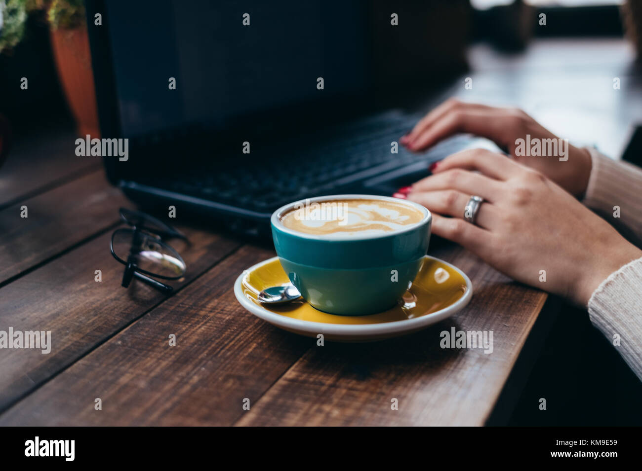 Tazza di caffè accanto a una donna con laptop Foto Stock