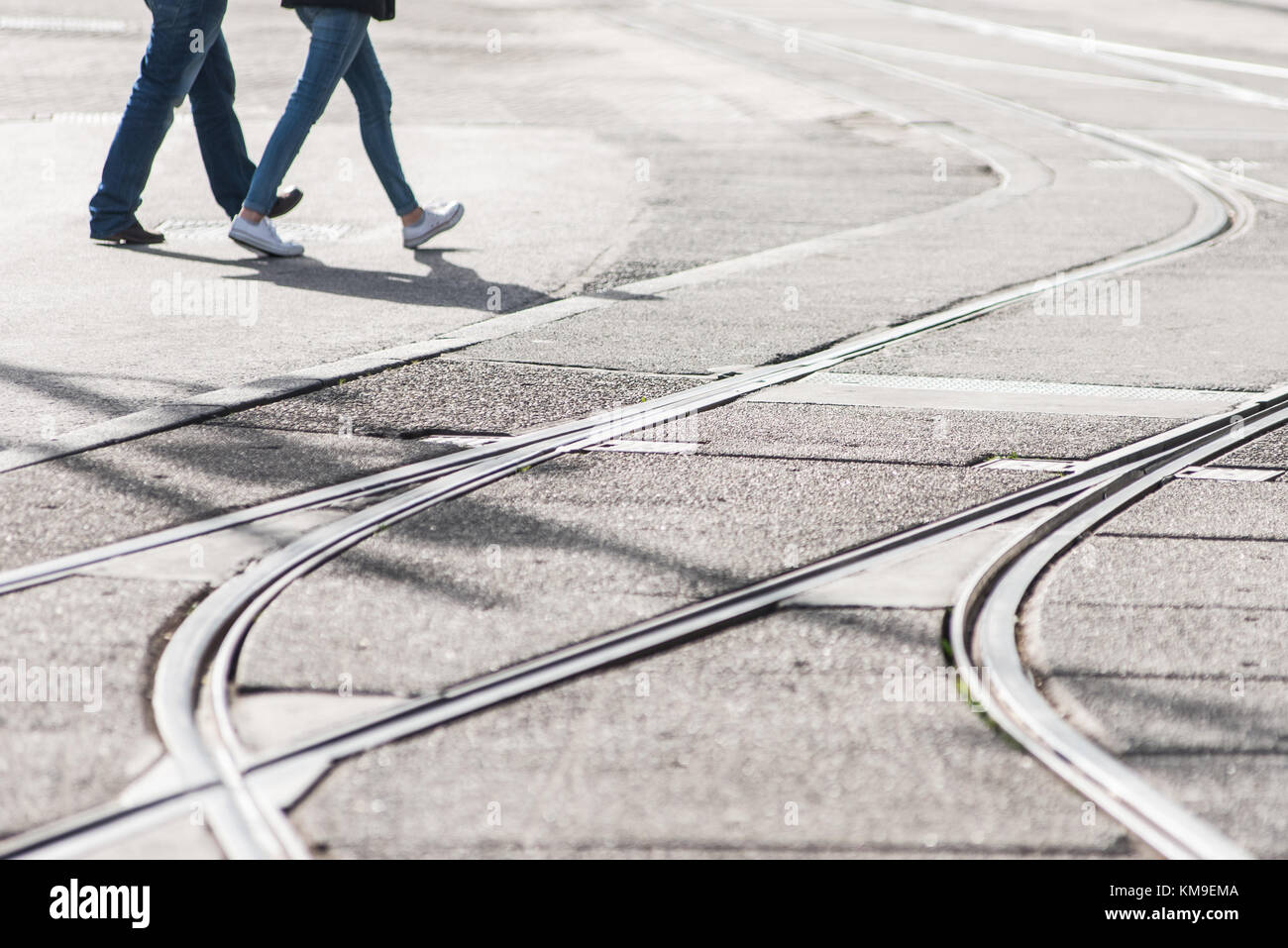 Due persone che attraversano i tracciafile in strada, Amsterdam, Olanda Foto Stock