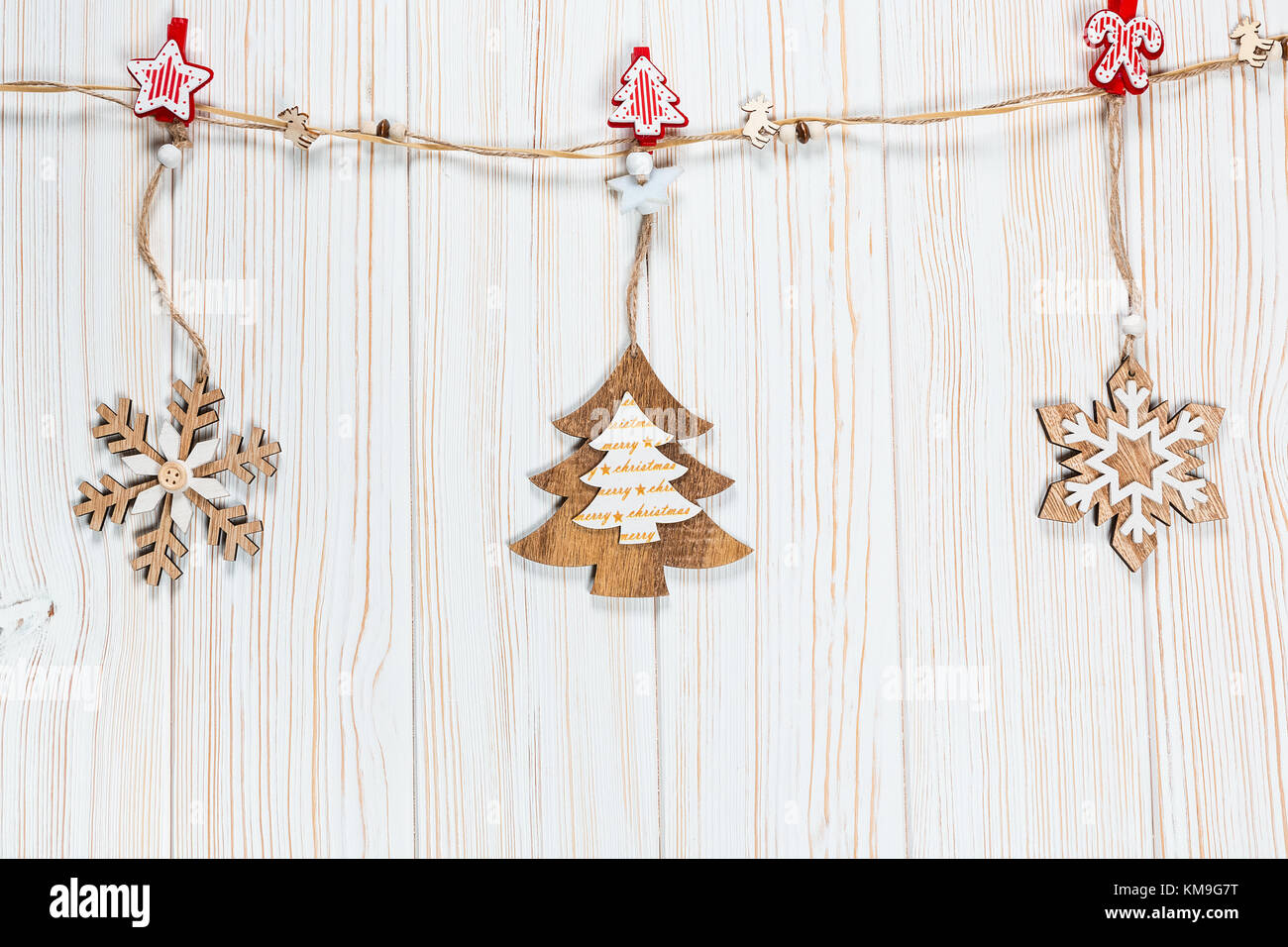 Il natale dei giocattoli di legno nella forma di un albero di natale e i fiocchi di neve pesare su una fune su un bianco sullo sfondo di legno. bellissimo messaggio di saluto festivo card wit Foto Stock