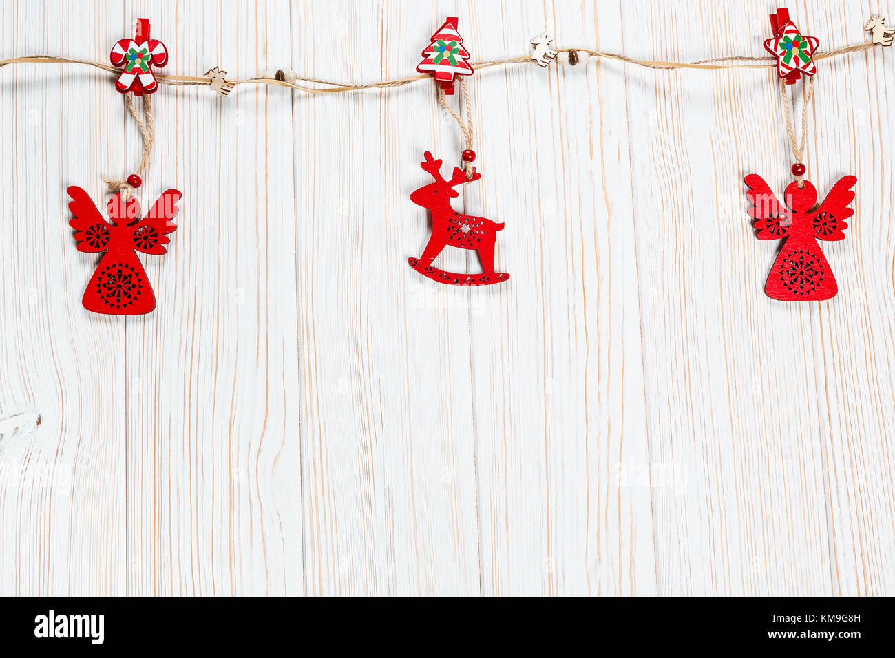 Natale rosso in legno giocattoli nella forma di un cervo e un angelico fune su un bianco sullo sfondo di legno. bellissimo messaggio di saluto festivo card con spazio libero Foto Stock