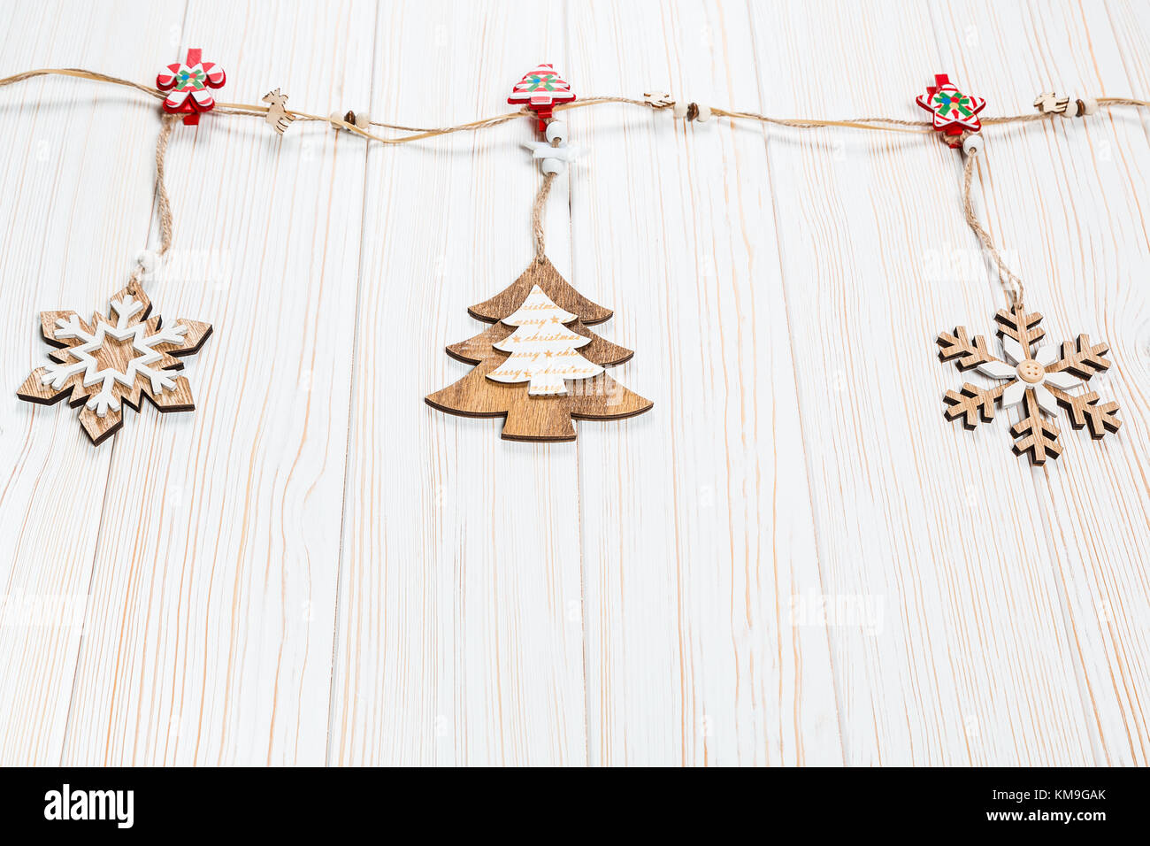 Il natale dei giocattoli di legno nella forma di un albero di natale e i fiocchi di neve pesare su una fune su un bianco sullo sfondo di legno. bellissimo messaggio di saluto festivo card wit Foto Stock