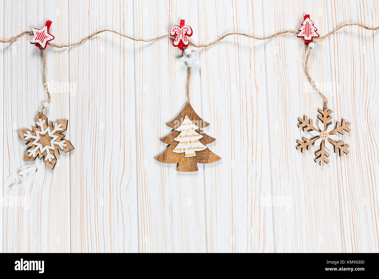 Il natale dei giocattoli di legno nella forma di un albero di natale e i fiocchi di neve pesare su una fune su un bianco sullo sfondo di legno. bellissimo messaggio di saluto festivo card wit Foto Stock