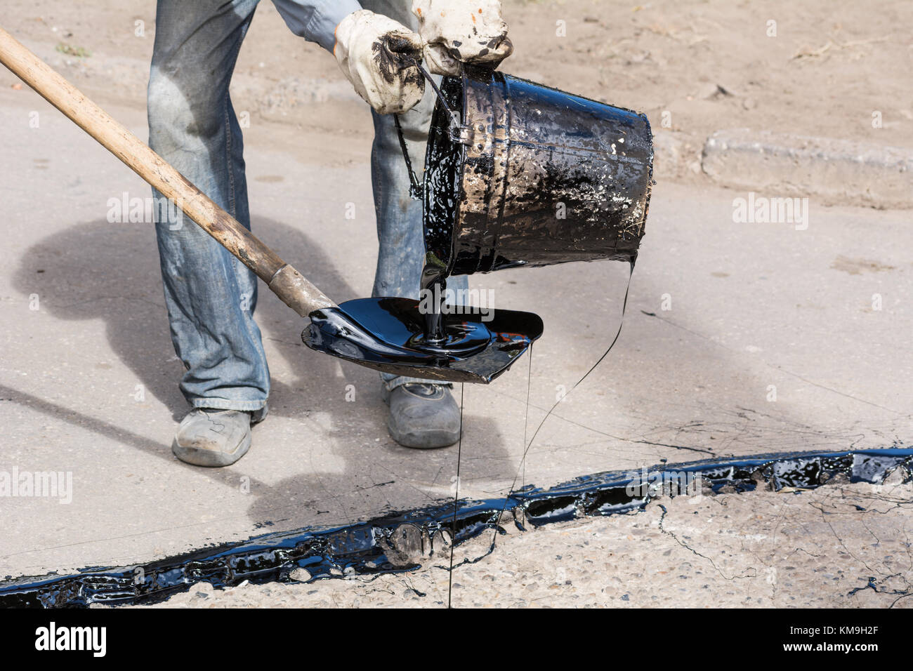 Riparazione su strada. Dettagli lavoro lavoratori, versare in resina della superficie stradale per coprire l'asfalto Foto Stock