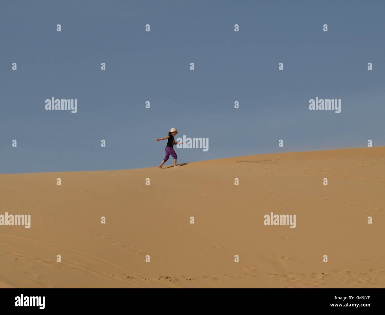 Ragazza che corre su di una duna di sabbia Foto Stock