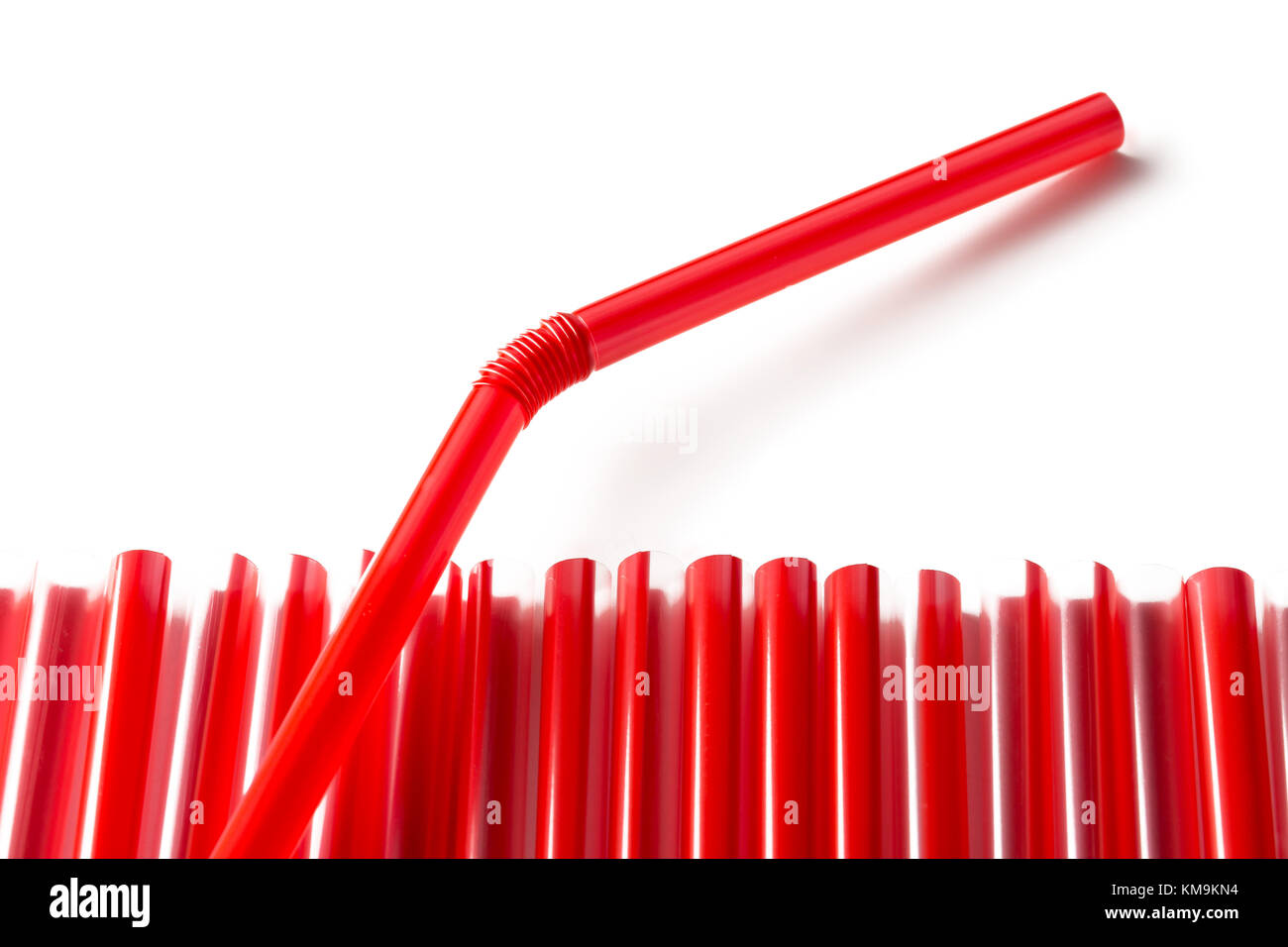 Fila di rosso cannucce in plastica con una cannuccia spuntavano su sfondo bianco Foto Stock