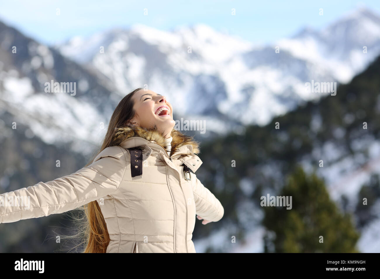 Ritratto di una donna entusiasta di ridere in inverno con una montagna innevata in background Foto Stock