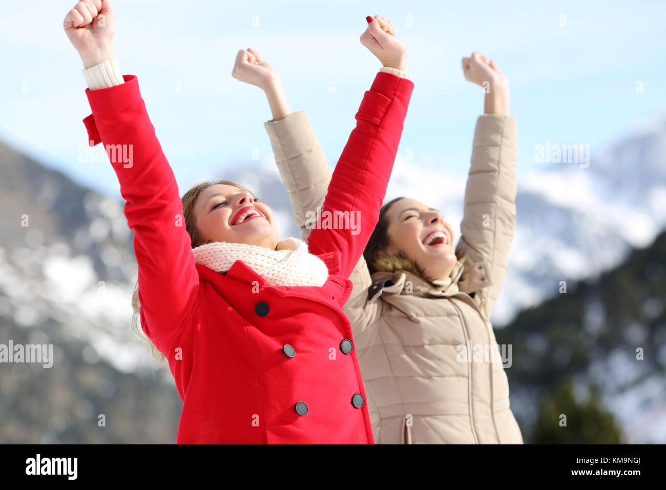 Due donne eccitato i bracci di sollevamento con una montagna innevata in background in inverno Foto Stock