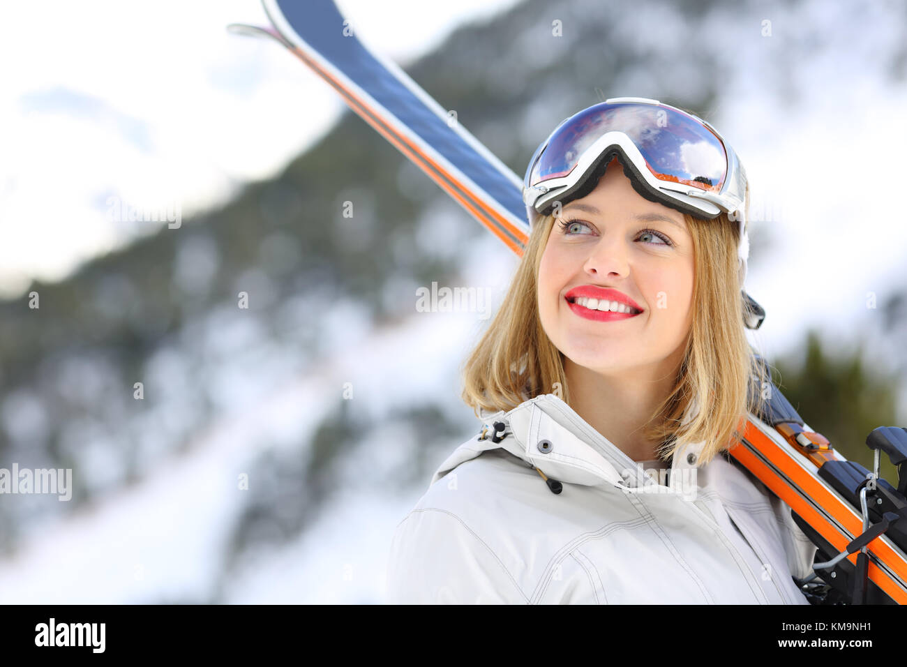 Ritratto di un buon sciatore guardando sopra con una montagna innevata in background Foto Stock