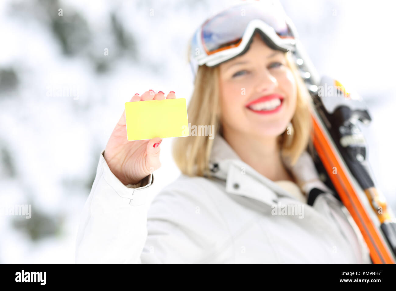 Vista anteriore verticale di un buon sciatore mano che mostra una scheda in un terreno in pendenza con una montagna innevata in background Foto Stock