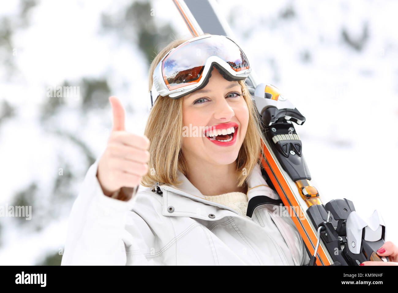 Ritratto di un buon sciatore con i pollici in su in un terreno in pendenza con una montagna innevata in background Foto Stock