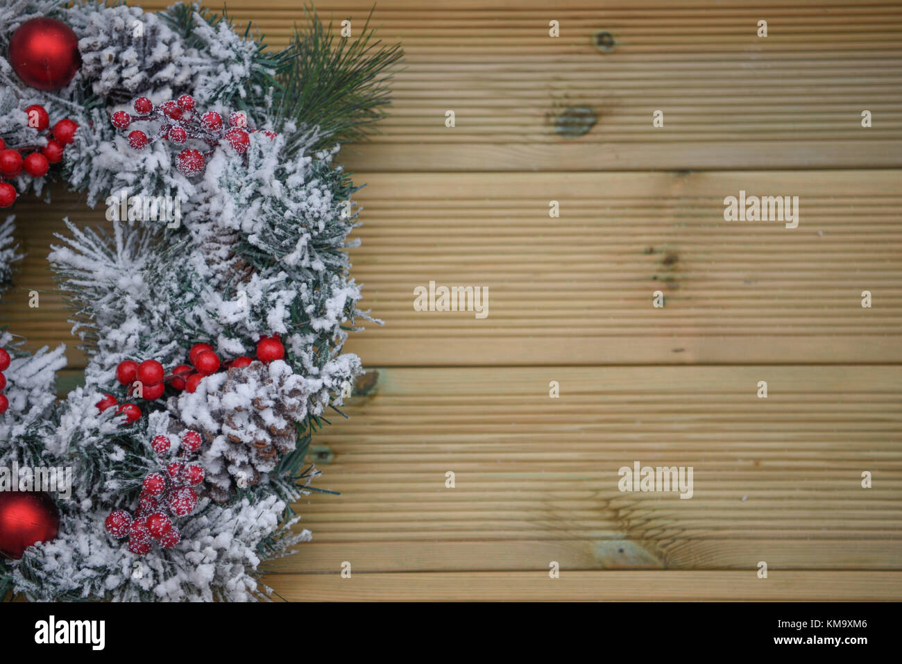 Natale immagine fotografia di un verde pino corona ricoperta di neve con bacche rosse e rustico in legno naturale sullo sfondo Foto Stock