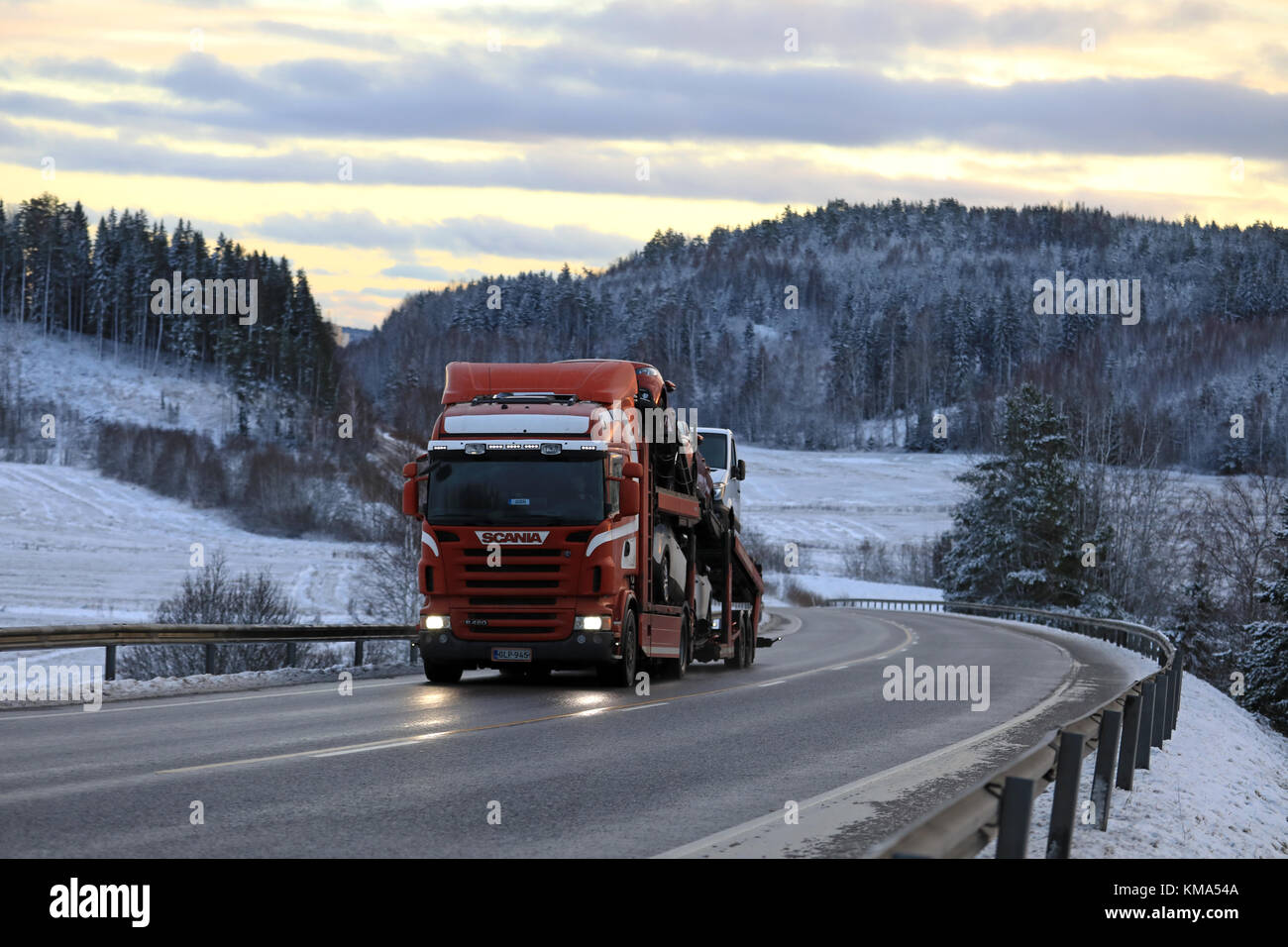 Salo, Finlandia - 2 dicembre 2017: rosso scania r480 auto vettore cale nuova vettura al tramonto lungo la strada in inverno. Foto Stock
