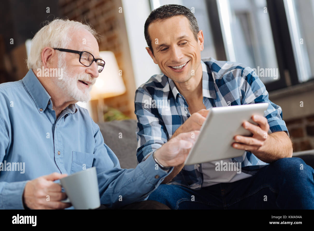 Uomo anziano e suo figlio discutendo articolo online Foto Stock