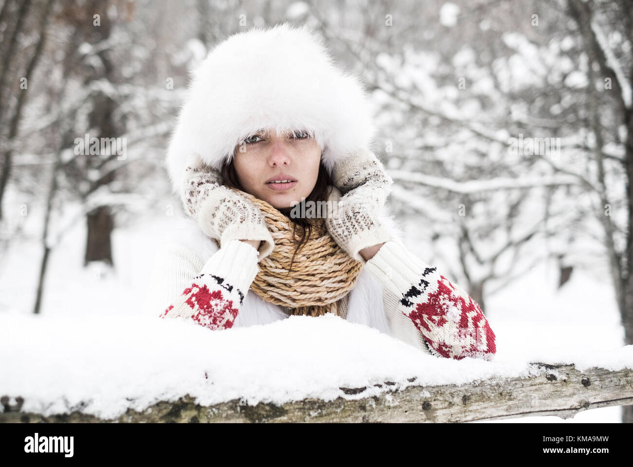 Giovane donna congelamento nella foresta di neve. con cappotto invernale maglia, sciarpa e cappello Foto Stock