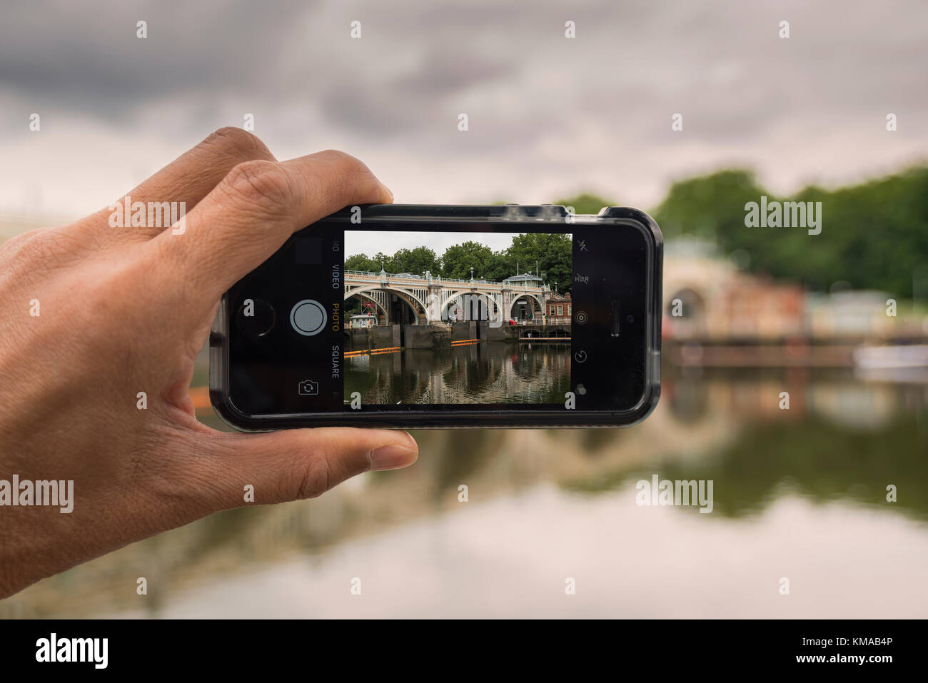 Un maschio di scattare foto di Richmond Lock e la passerella sul fiume Tamigi con iPhone SE, Richmond, Londra Foto Stock