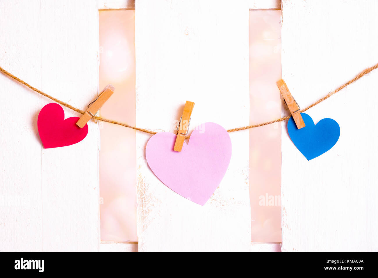 Il giorno di san valentino immagine con un grande cuore rosa al centro, uno rosso e uno blu sui lati, costituito da carta e legato a una stringa con clip in legno Foto Stock