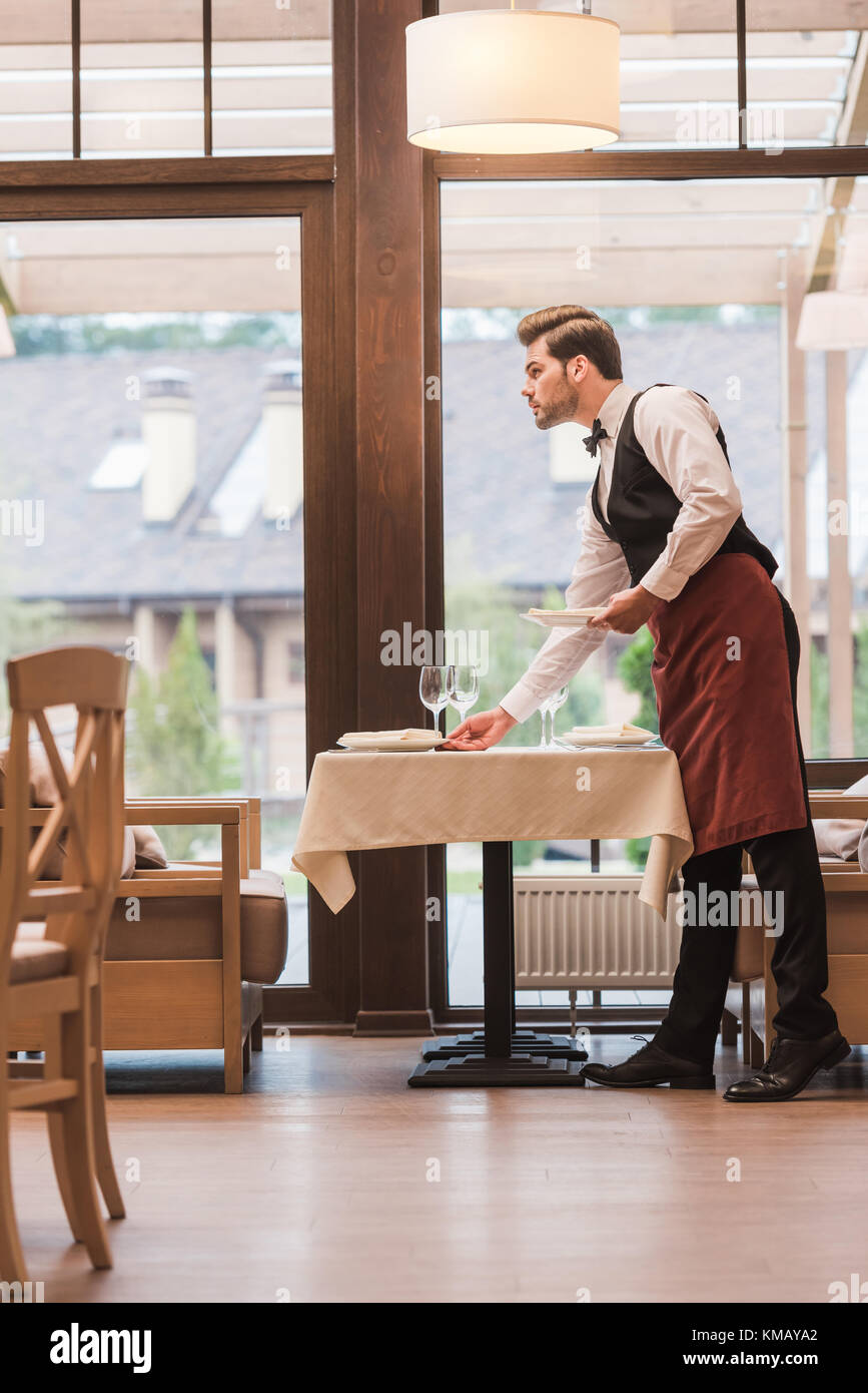 Cameriere che serve piatti sul tavolo Foto Stock