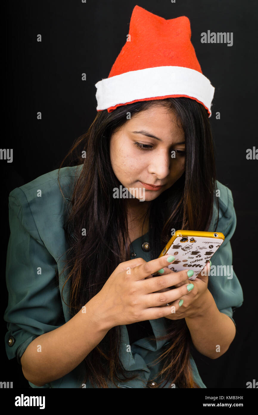 Ragazza con cappello a Natale guardando al telefono. Foto Stock