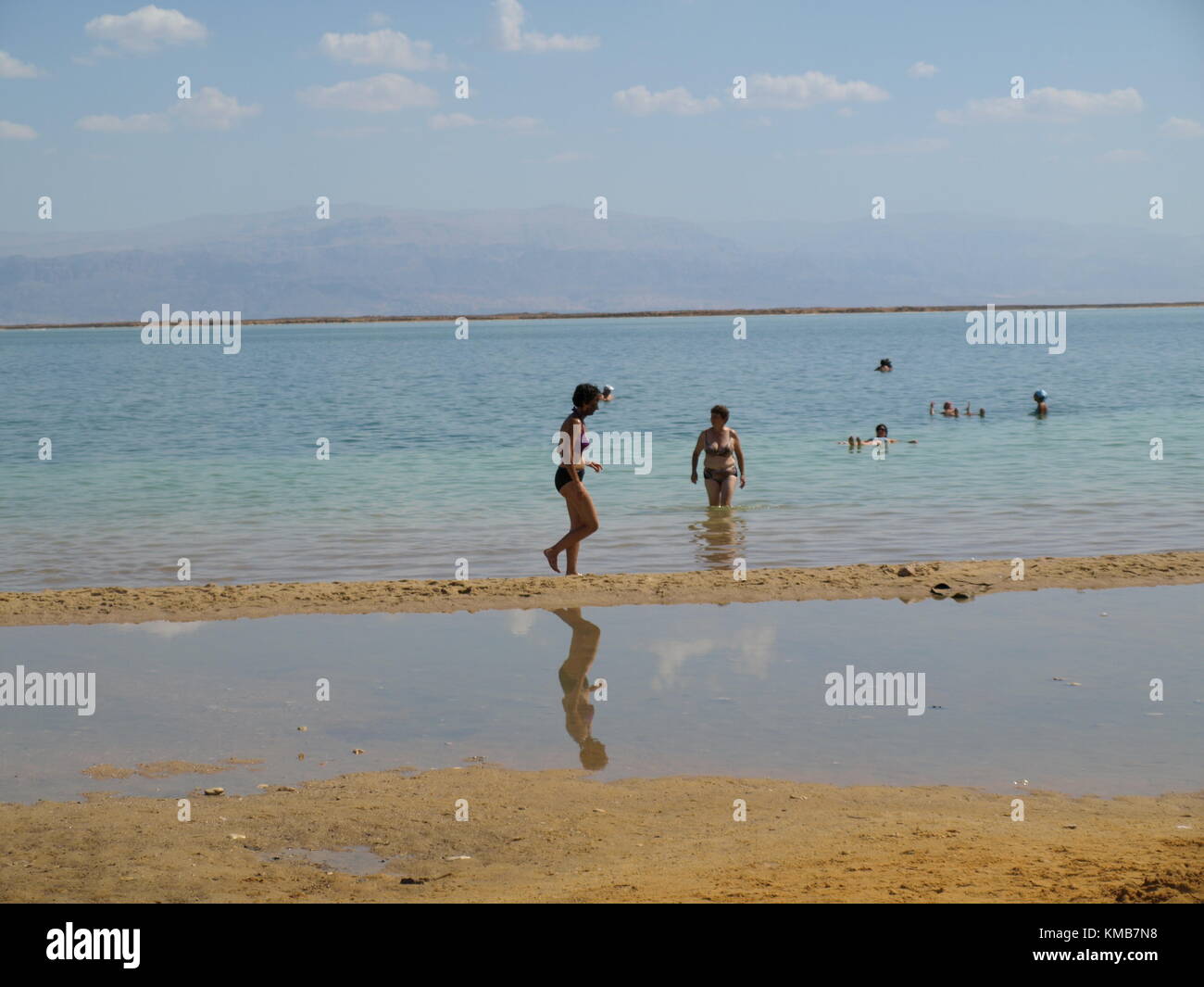 Una donna con minerale di fango sul suo viso è di camminare sulla spiaggia del Mar Morto Foto Stock