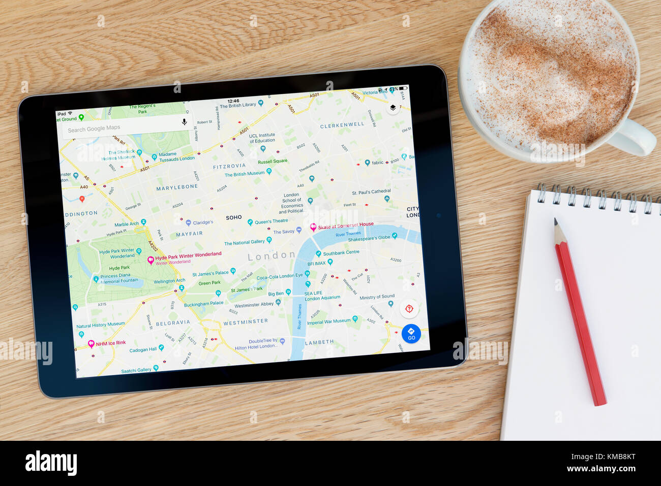 Le mappe di Google le caratteristiche di app su iPad un dispositivo tablet pc che si appoggia su una tavola di legno accanto a un blocco note e matita e una tazza di caffè (solo editoriale). Foto Stock