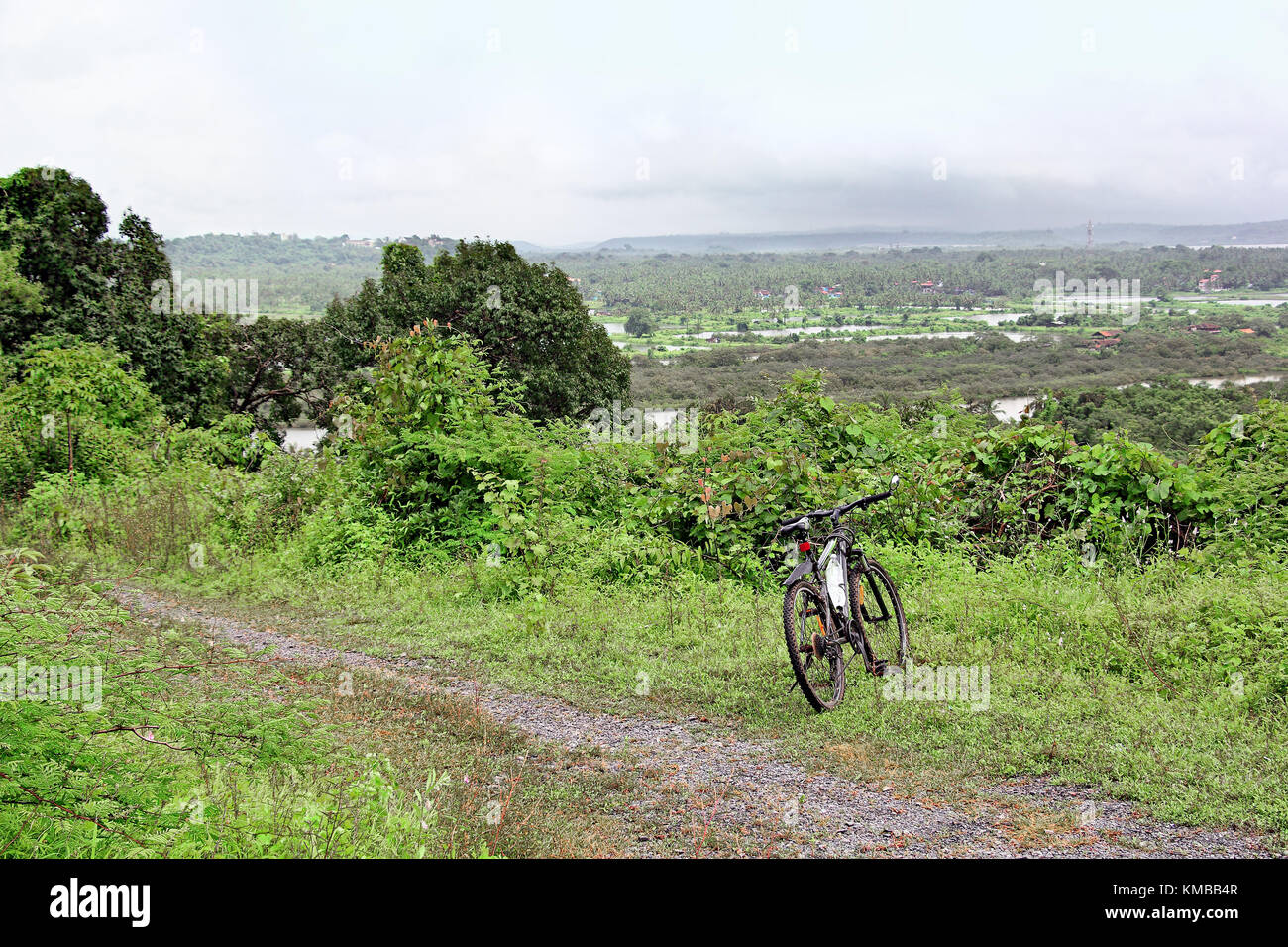 Ciclo durante parcheggiata fuori strada in bicicletta lungo ruvido paesaggio strade coperte di vegetazione lussureggiante e panoramiche vedute aeree vicino Bambolim in Goa, India Foto Stock