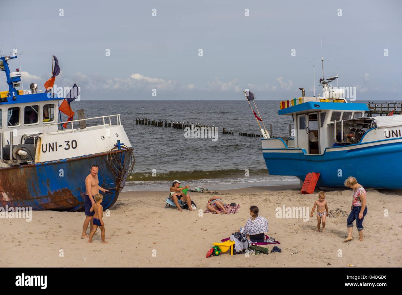I turisti si divertono tra le barche di pescatori sulla spiaggia del resort mielno. Foto Stock