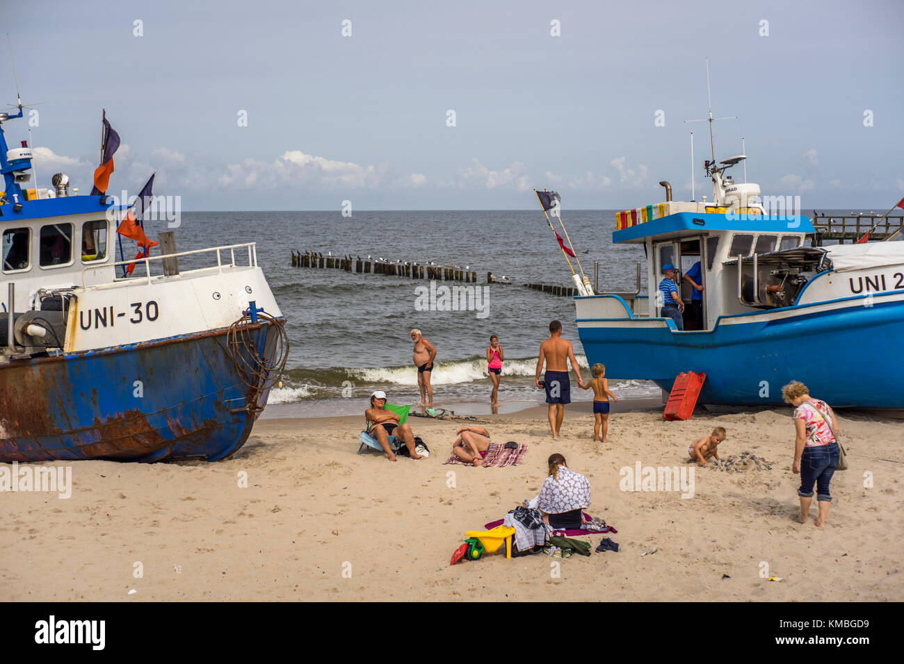 I vacanzieri si divertono tra le barche da pesca sulla spiaggia del resort Mielno. Foto Stock