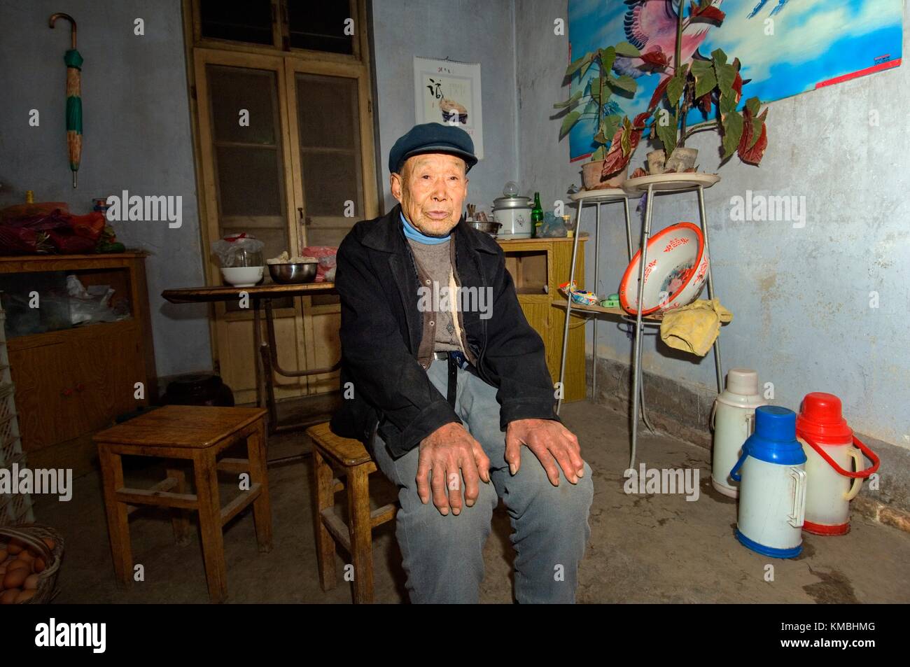 Anziano contadino seduto in agriturismo cucina nel borgo di poli vicino Penglai, Provincia di Shandong, Cina Foto Stock