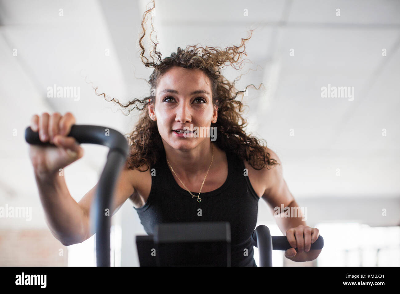 Determinata giovane donna che usa l'addestratore ellittico in palestra Foto Stock