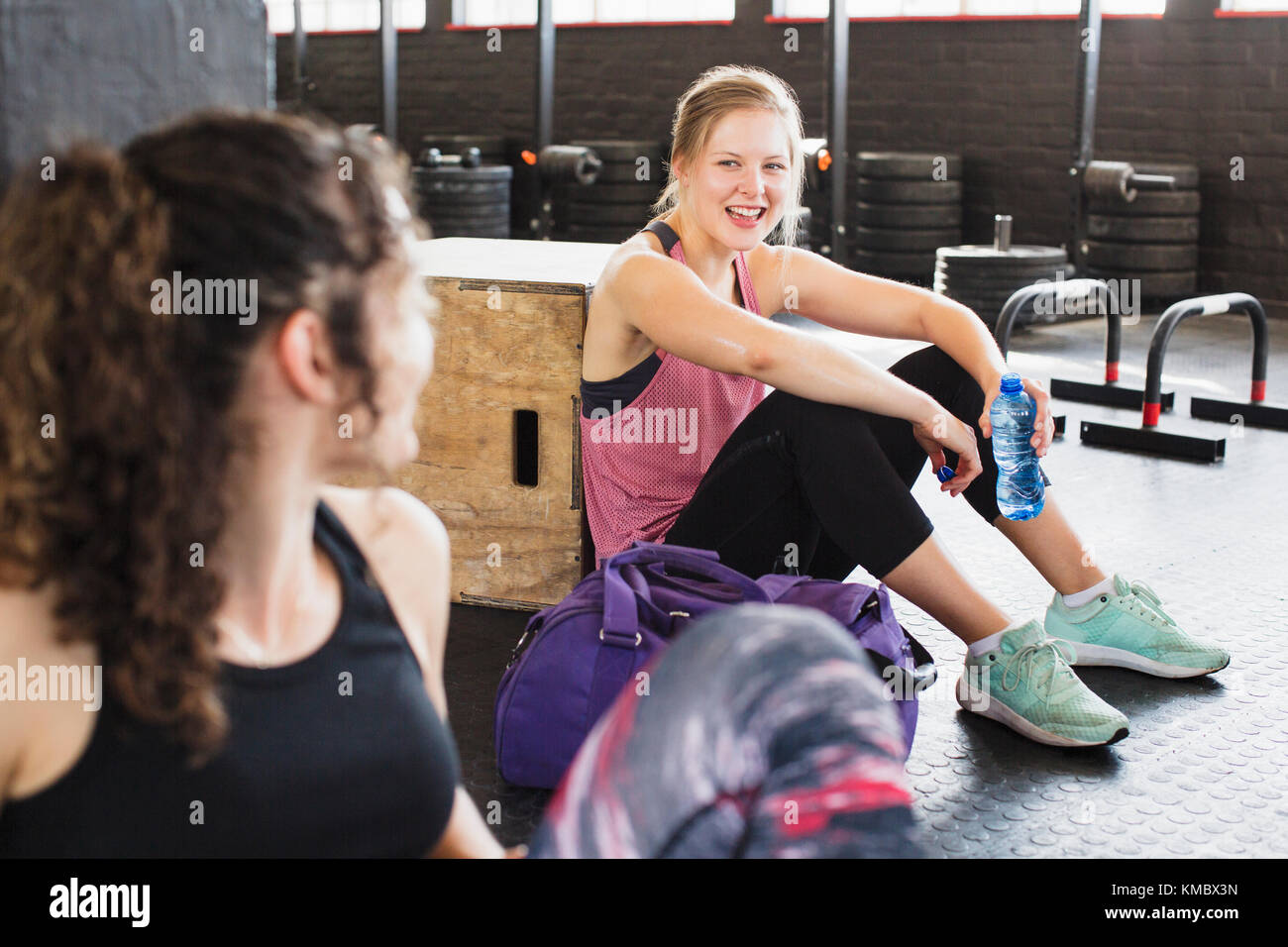 Sorridente giovani donne che riposano e acqua potabile post allenamento in palestra Foto Stock