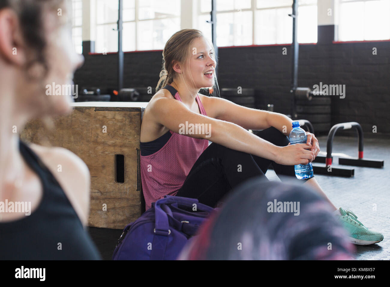 Sorridente giovane donna che riposa e acqua potabile post allenamento in palestra Foto Stock
