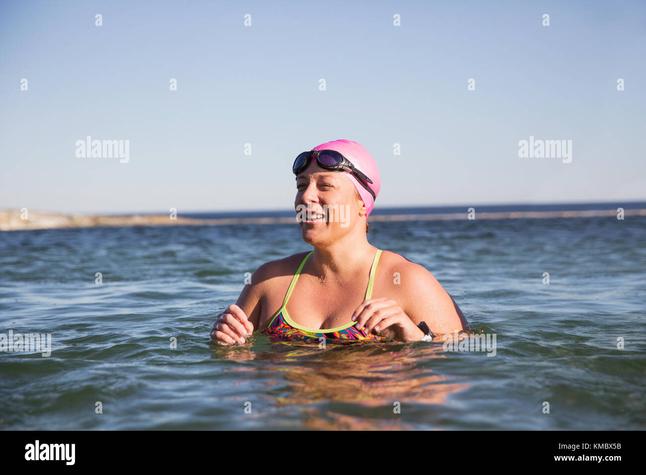 Donna sorridente open water nuotatore nuoto nella soleggiata ocean Foto Stock
