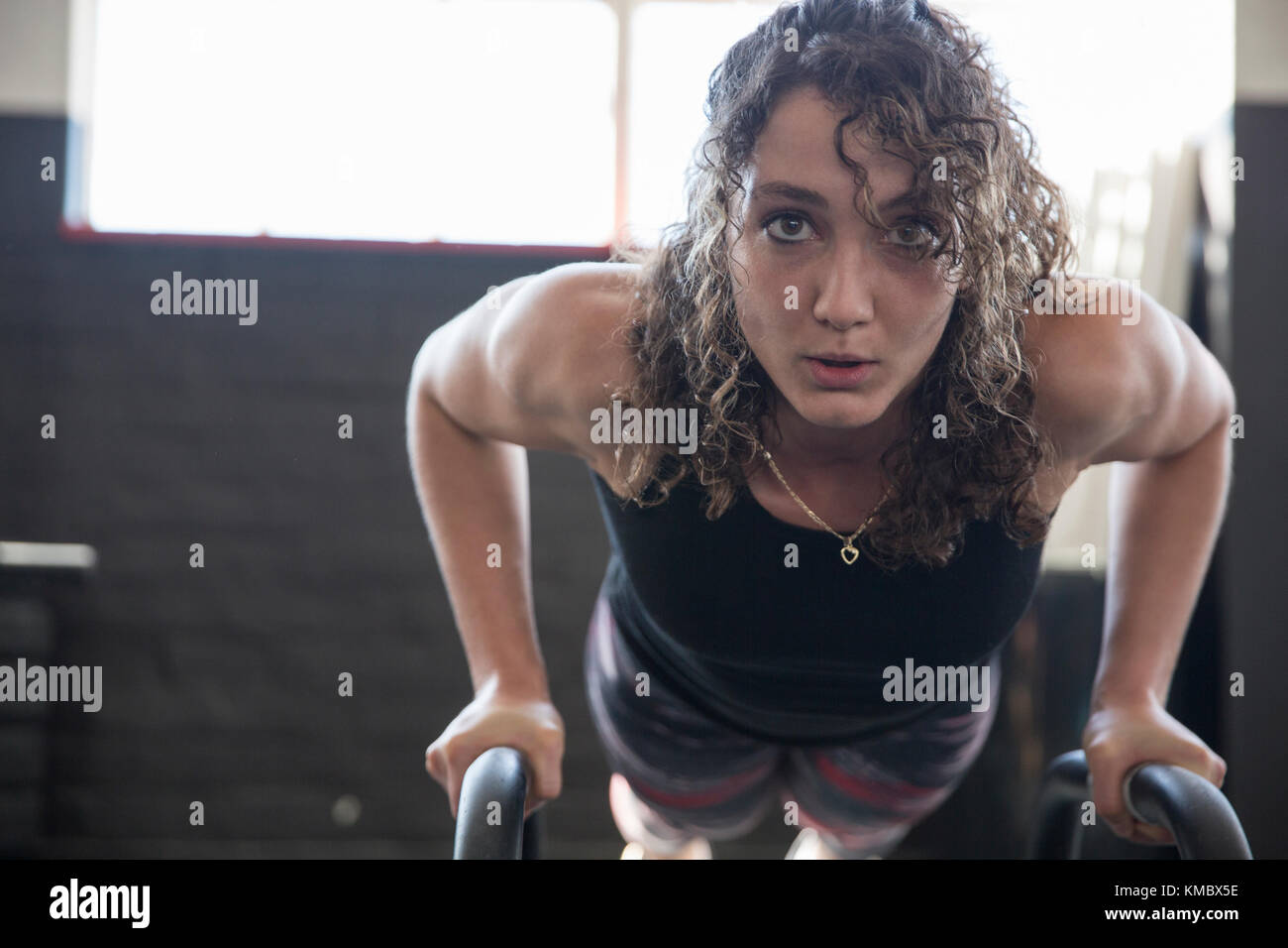 Ritratto determinata giovane donna che fa push-up con attrezzature in palestra Foto Stock